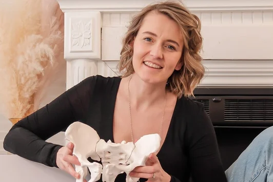 Doula souriante tenant un modèle anatomique du bassin