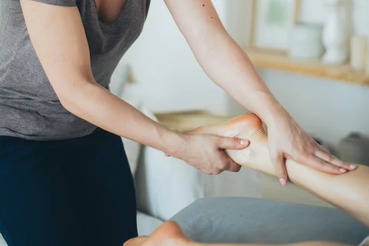 Ostéopathe effectuant un traitement doux sur le pied d'une cliente