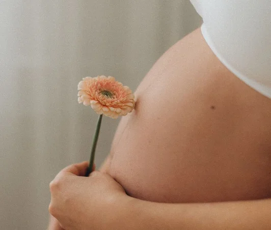 Femme enceinte tenant une fleur